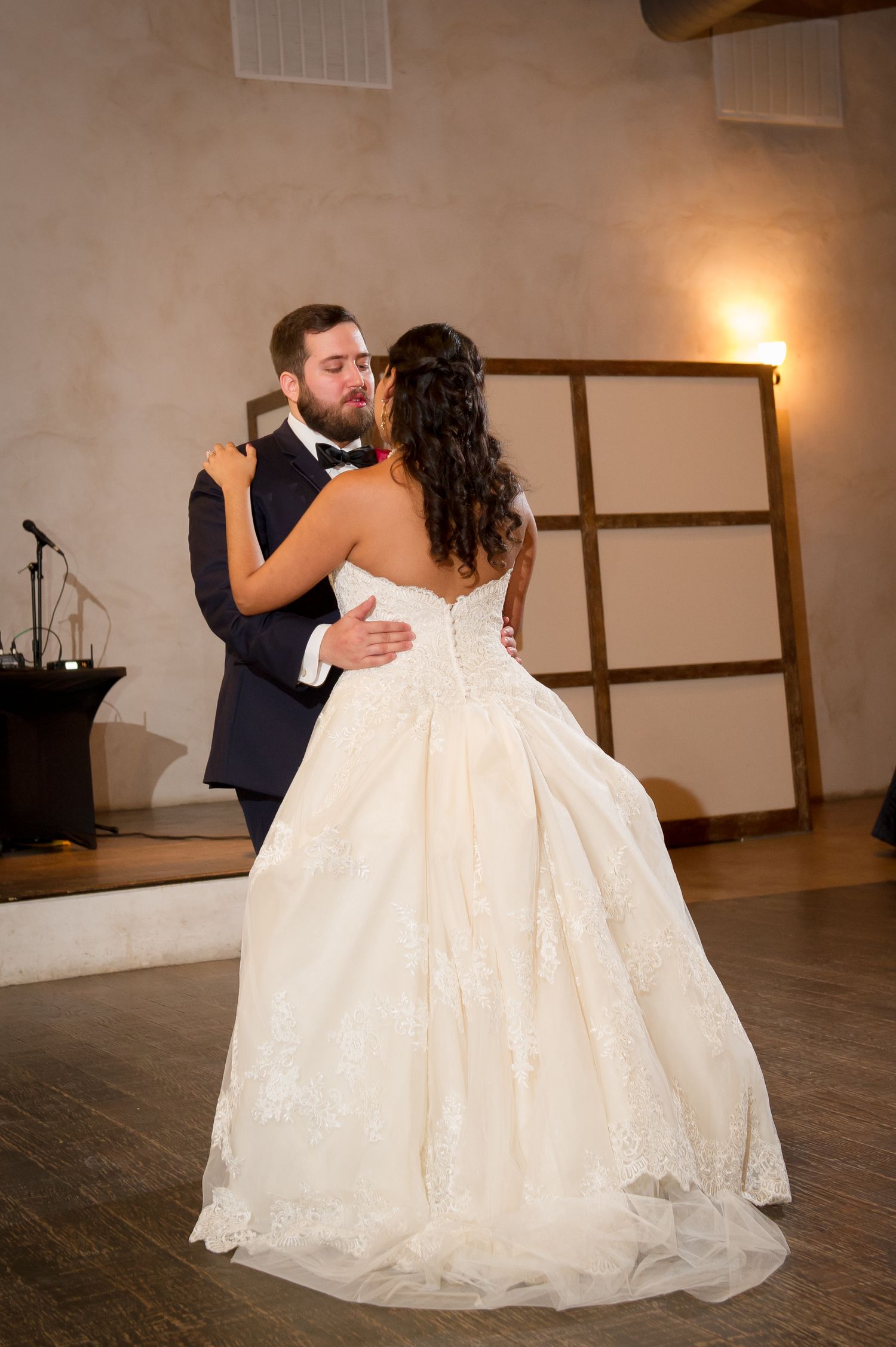 Couple shares romantic first dance in elegant reception venue with warm lighting.