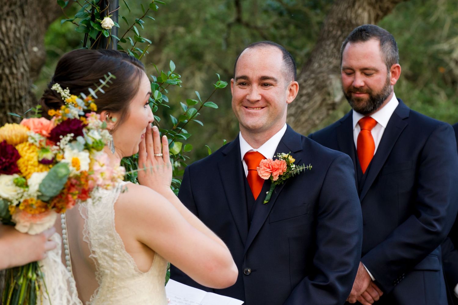 Wedding couple shares an emotional moment during outdoor ceremony with autumn-colored floral bouquet.