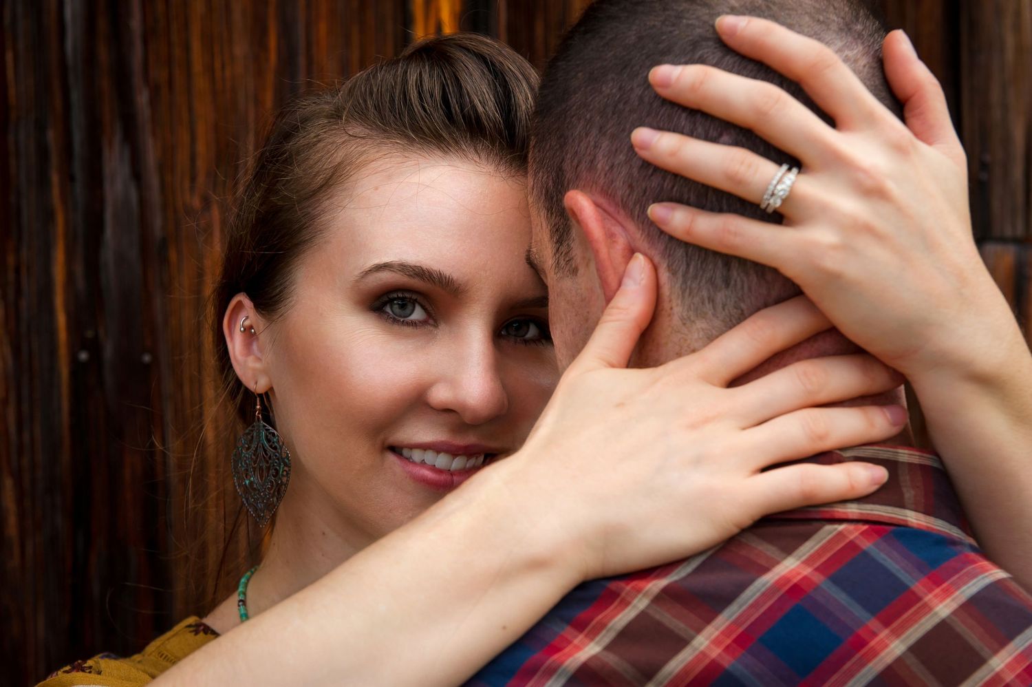 Close-up artistic wedding portrait against rustic wooden wall background.