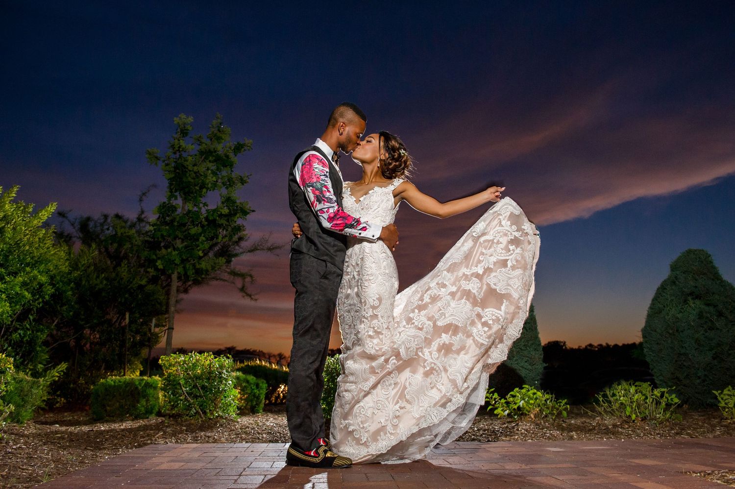 Dramatic sunset wedding portraits with silhouettes against colorful evening sky.