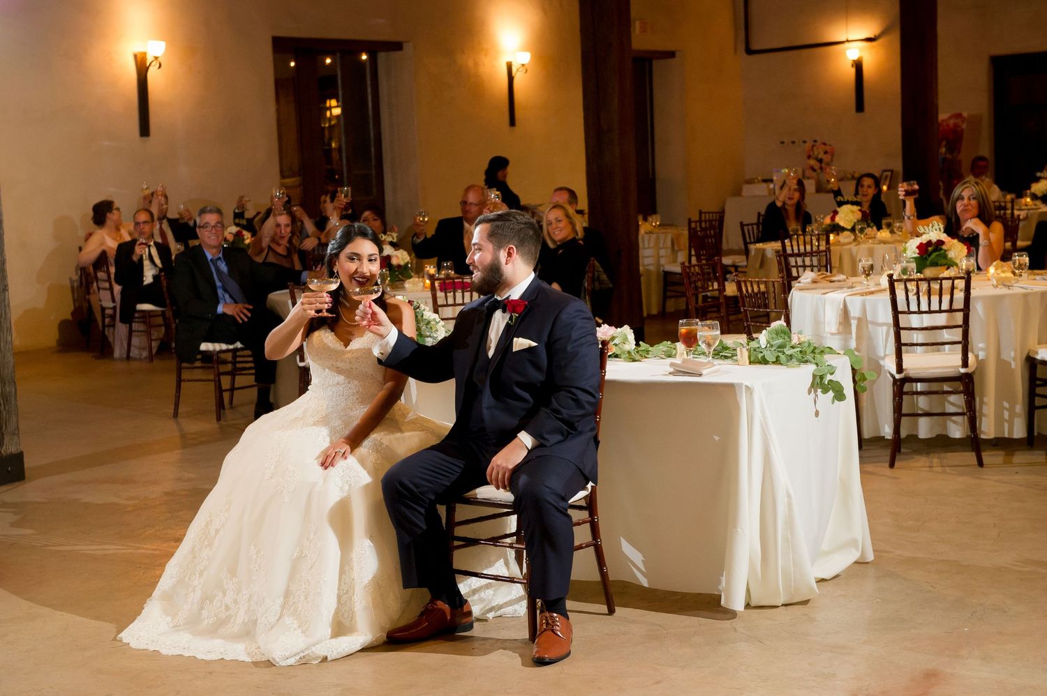 Wedding reception dance captured in elegant venue with guests watching from tables.