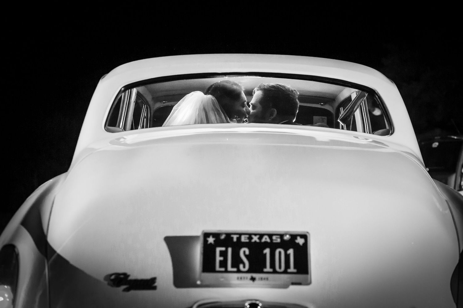 Classic white vintage car with fins and chrome details parked at a wedding venue.
