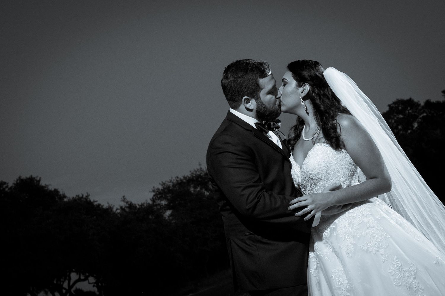 Dramatic black and white wedding portraits captured against dark background.