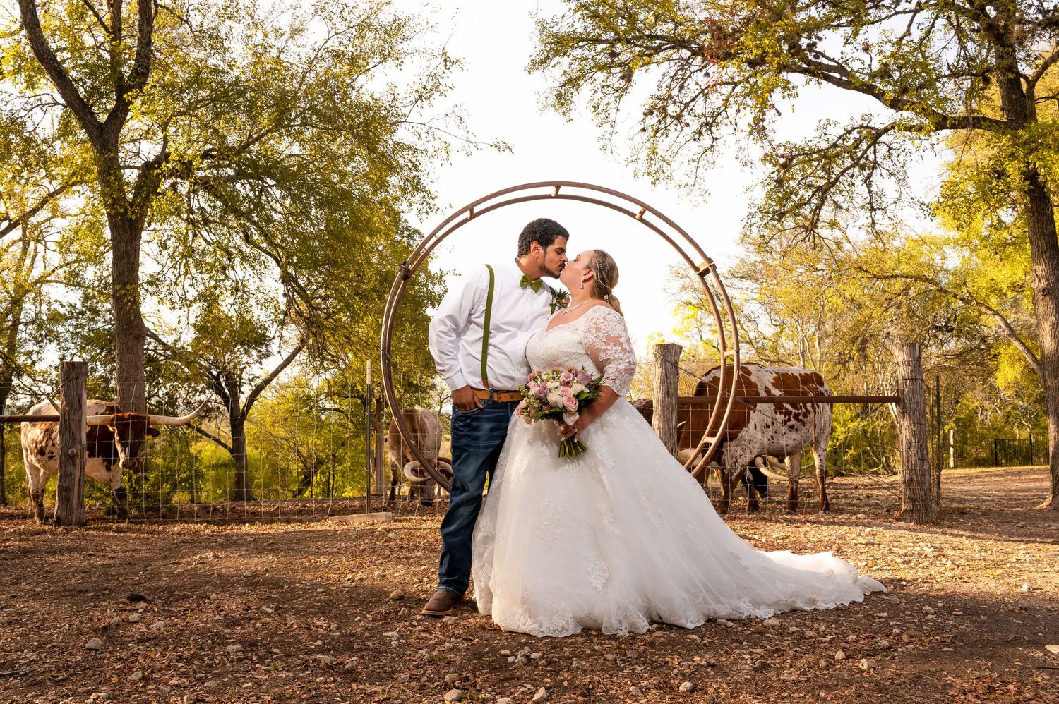 Wedding couple under rustic arch surrounded by autumn trees.