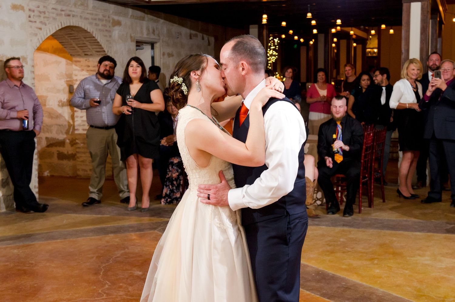 Couples dancing together at an indoor wedding reception with exposed brick walls and warm lighting.