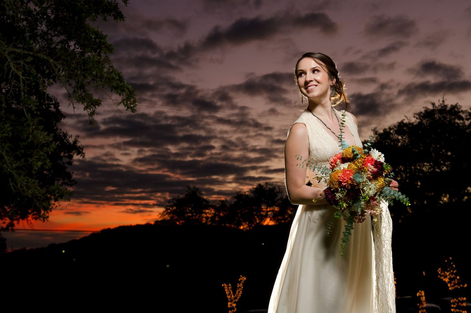 Romantic wedding portraits captured against a stunning purple sunset sky.