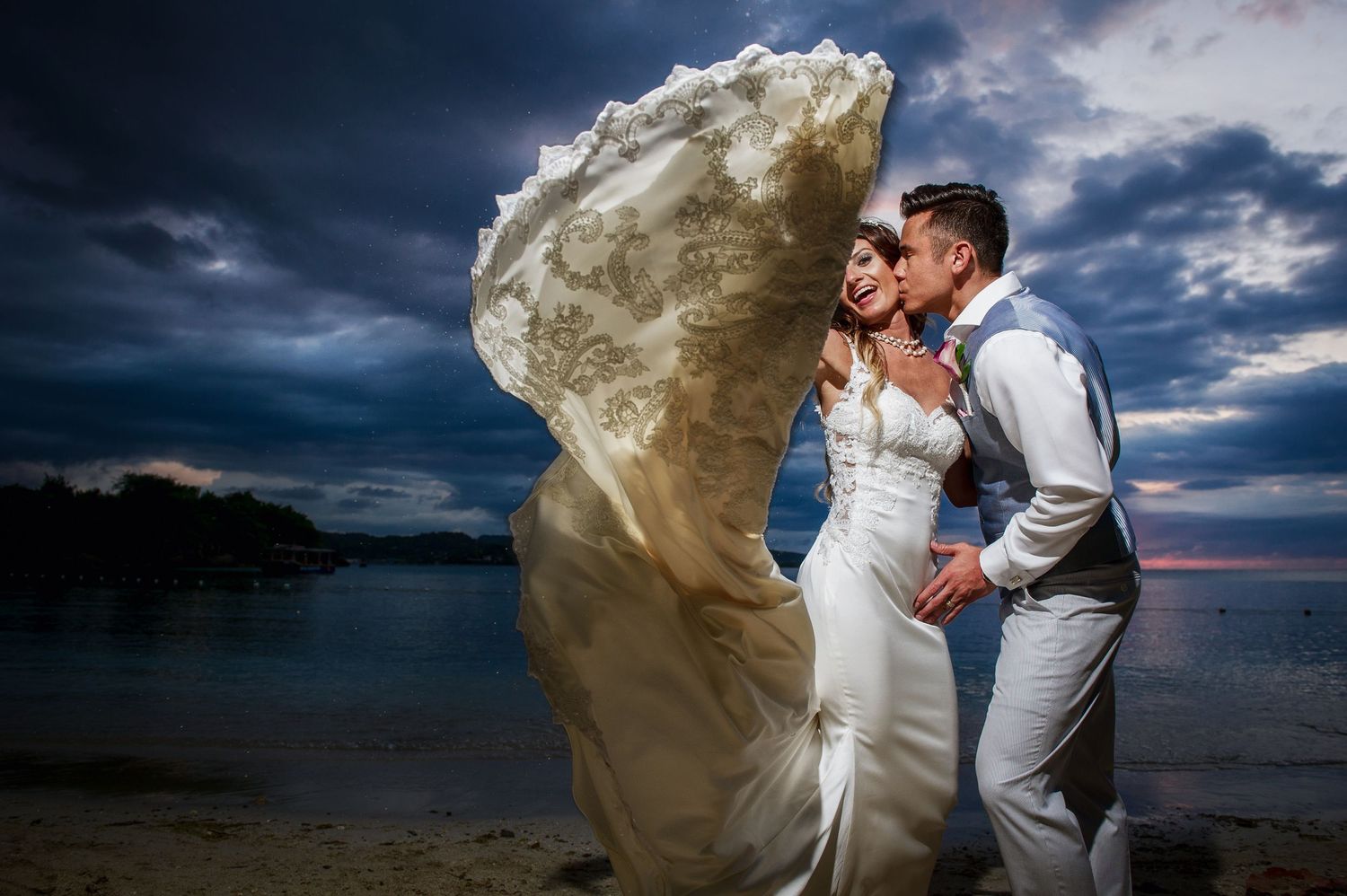 Coastal wedding photos with flowing white dress against stormy sky backdrop.