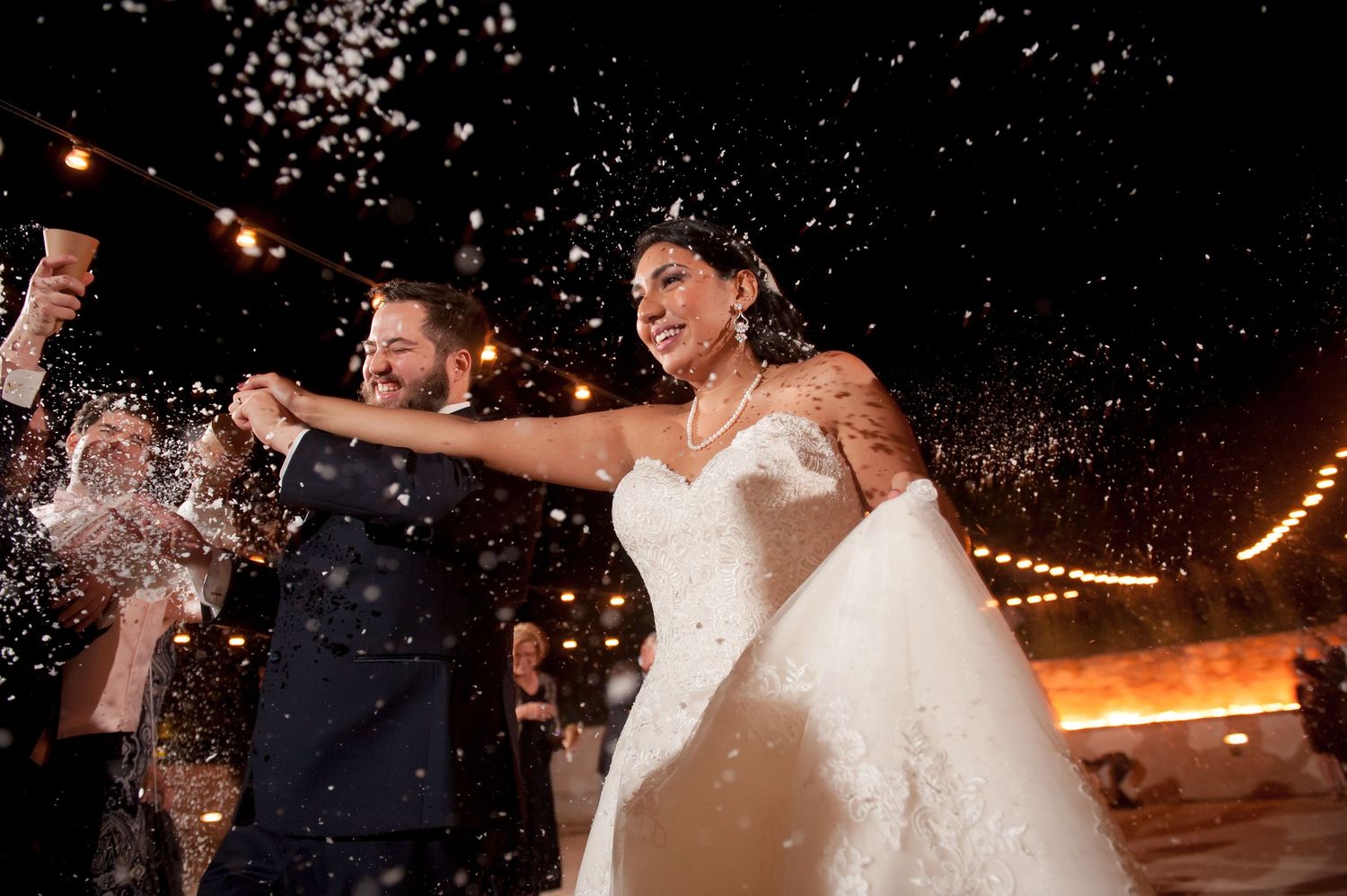 Wedding party celebrates with sparklers during a nighttime outdoor reception.