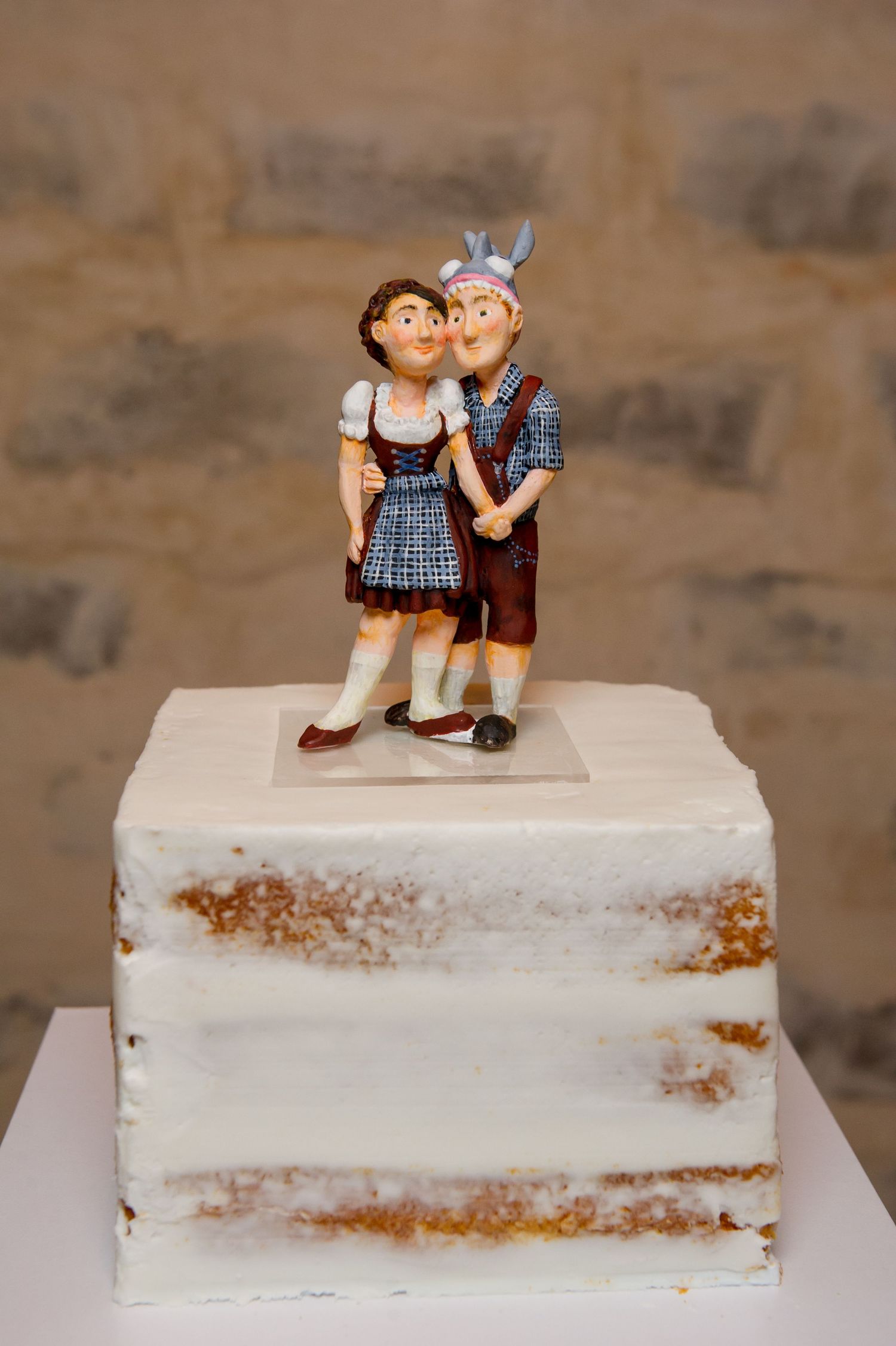 Cute vintage-style cake topper figurines on a rustic white wedding cake.