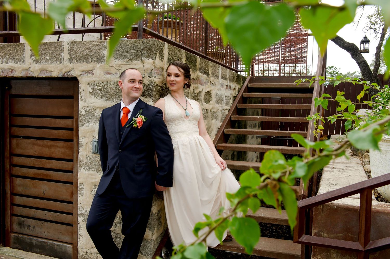 Wedding couple shares emotional first look on rustic stone patio with wooden railings.