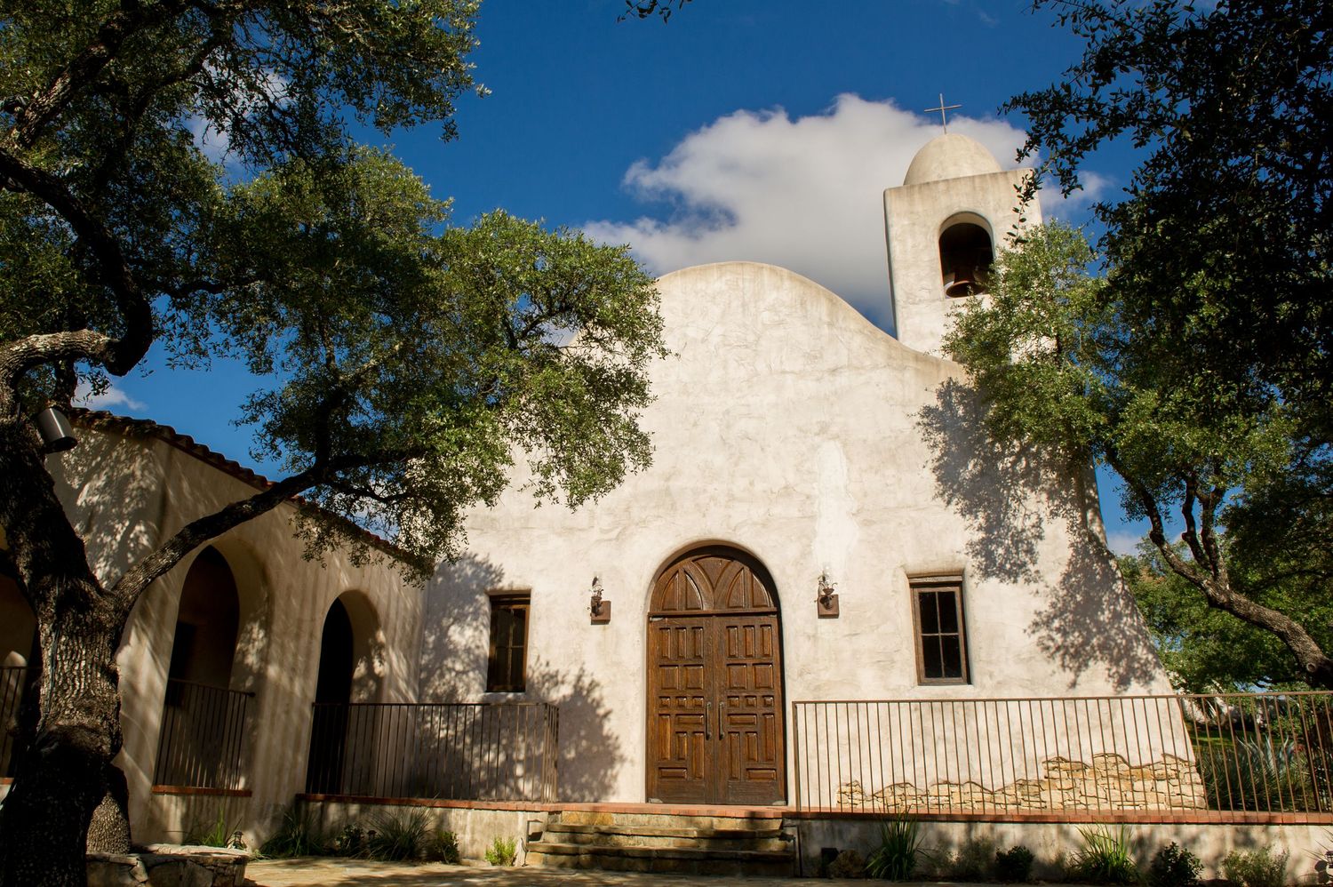 Historic white stone mission architecture with arched doorways under blue sky.
