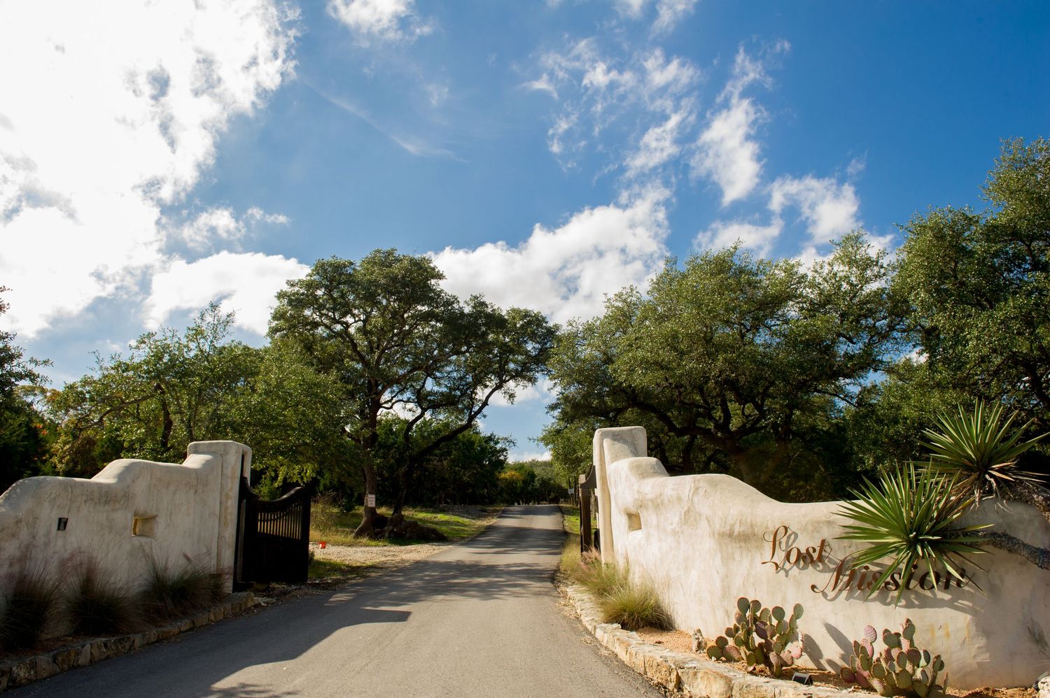 Panoramic view of a rustic white stone mission building with winding path.
