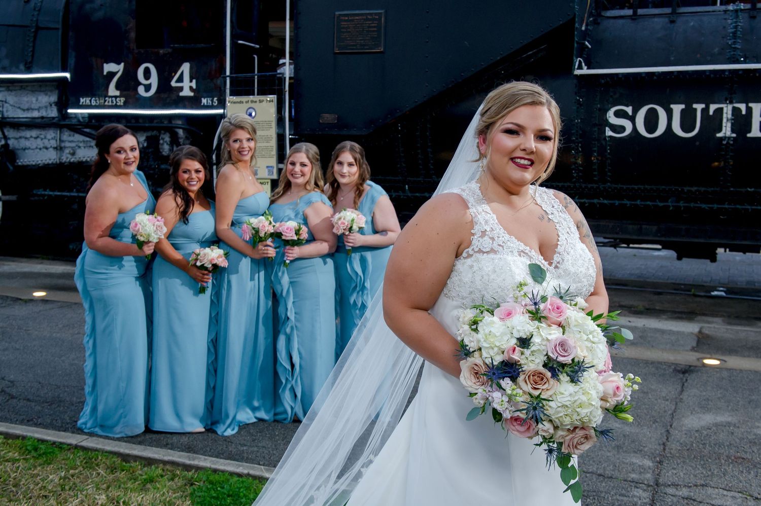 Wedding group poses casually along black Southern Pacific train car.
