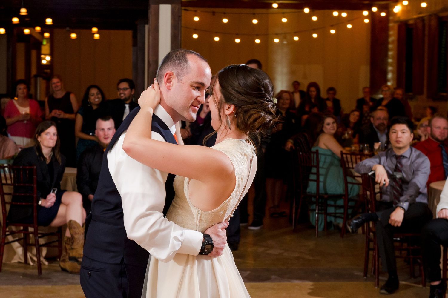 Wedding couples dancing intimately under romantic string light decorations.