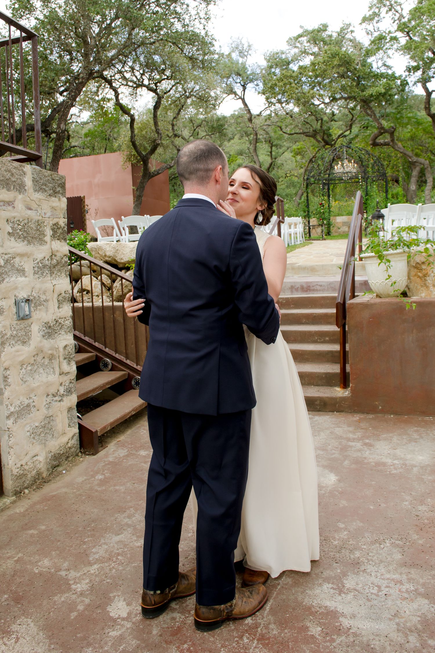 Intimate wedding first look moment captured on stone patio surrounded by lush greenery.