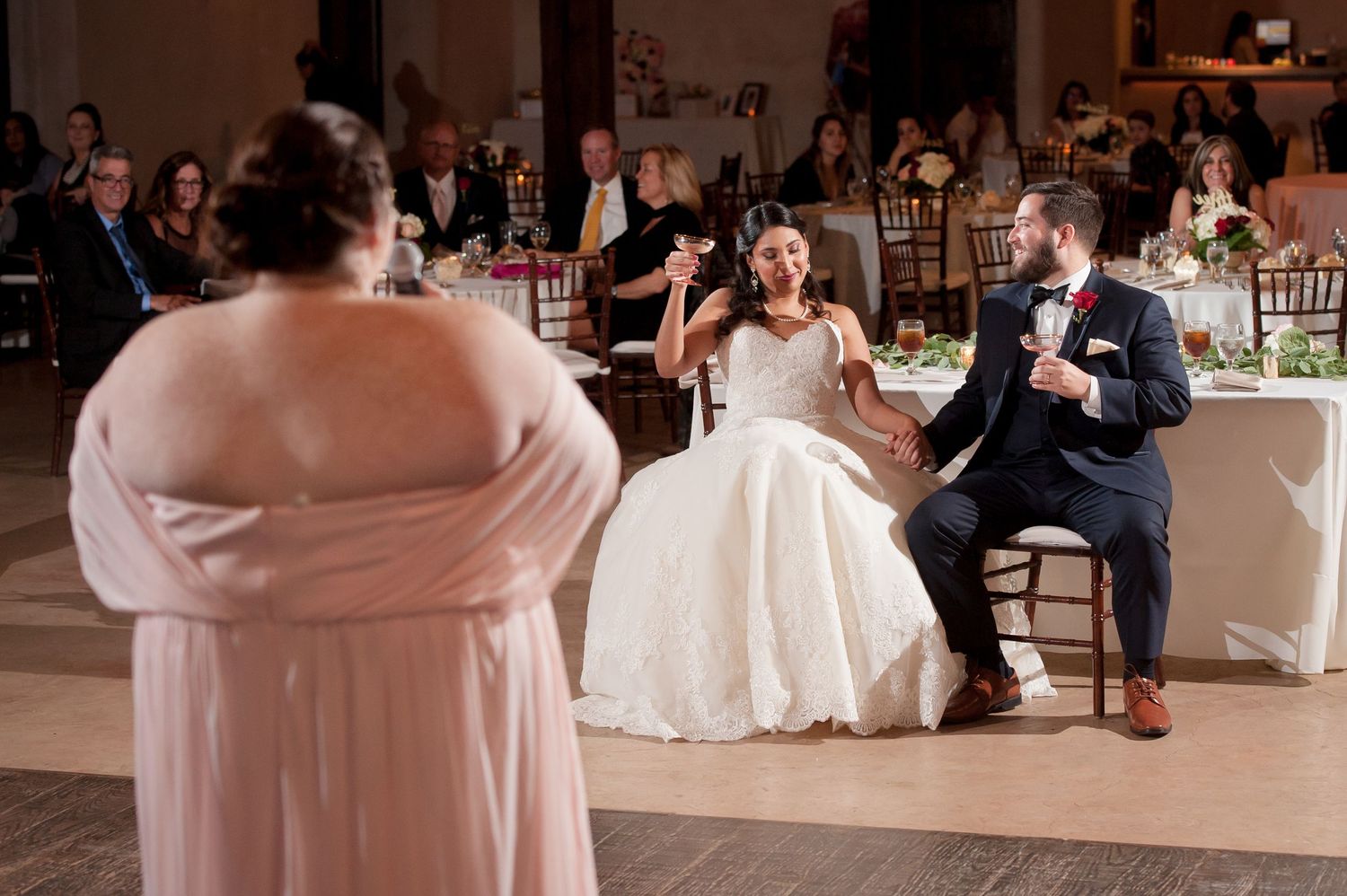 Wedding party members dance and celebrate during an indoor reception.