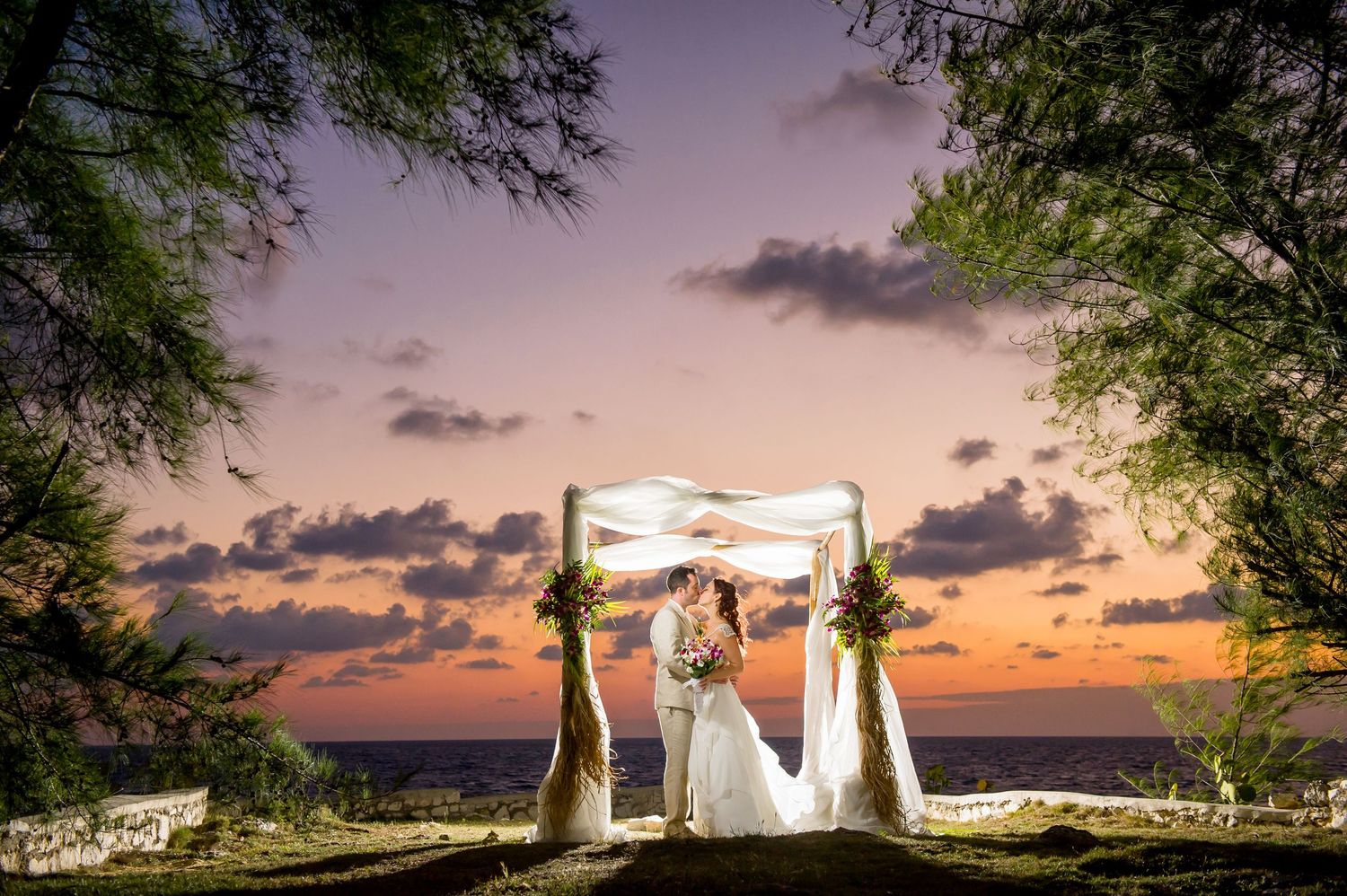 Sunset wedding venue with dramatic purple sky and illuminated white tent.