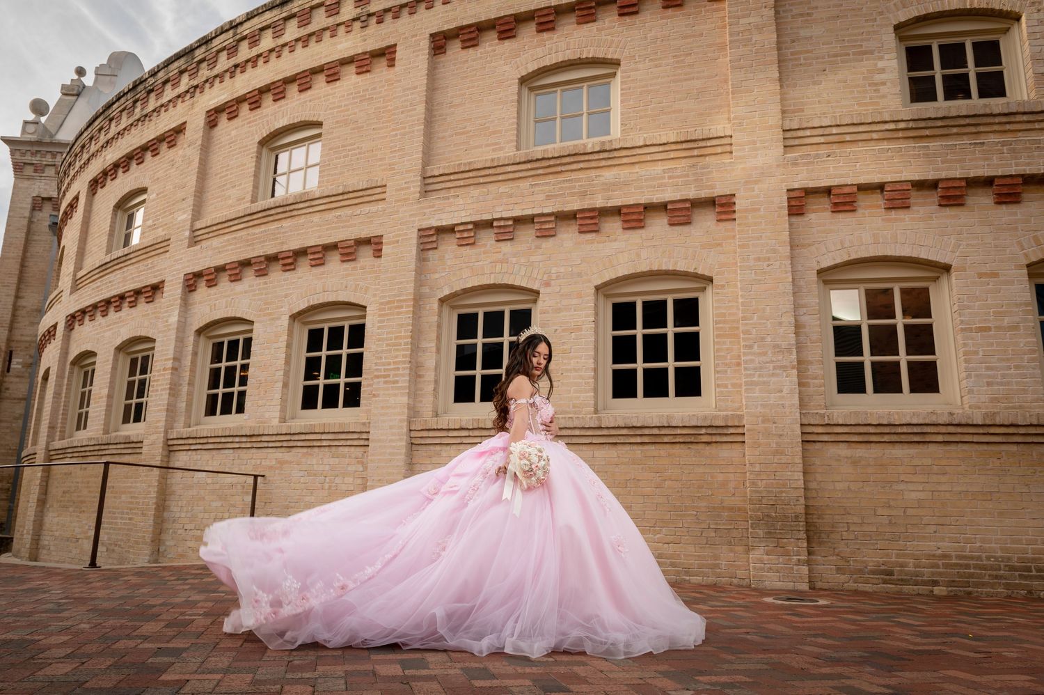 Flowing pink ballgown dress photographed against historic stone architecture.