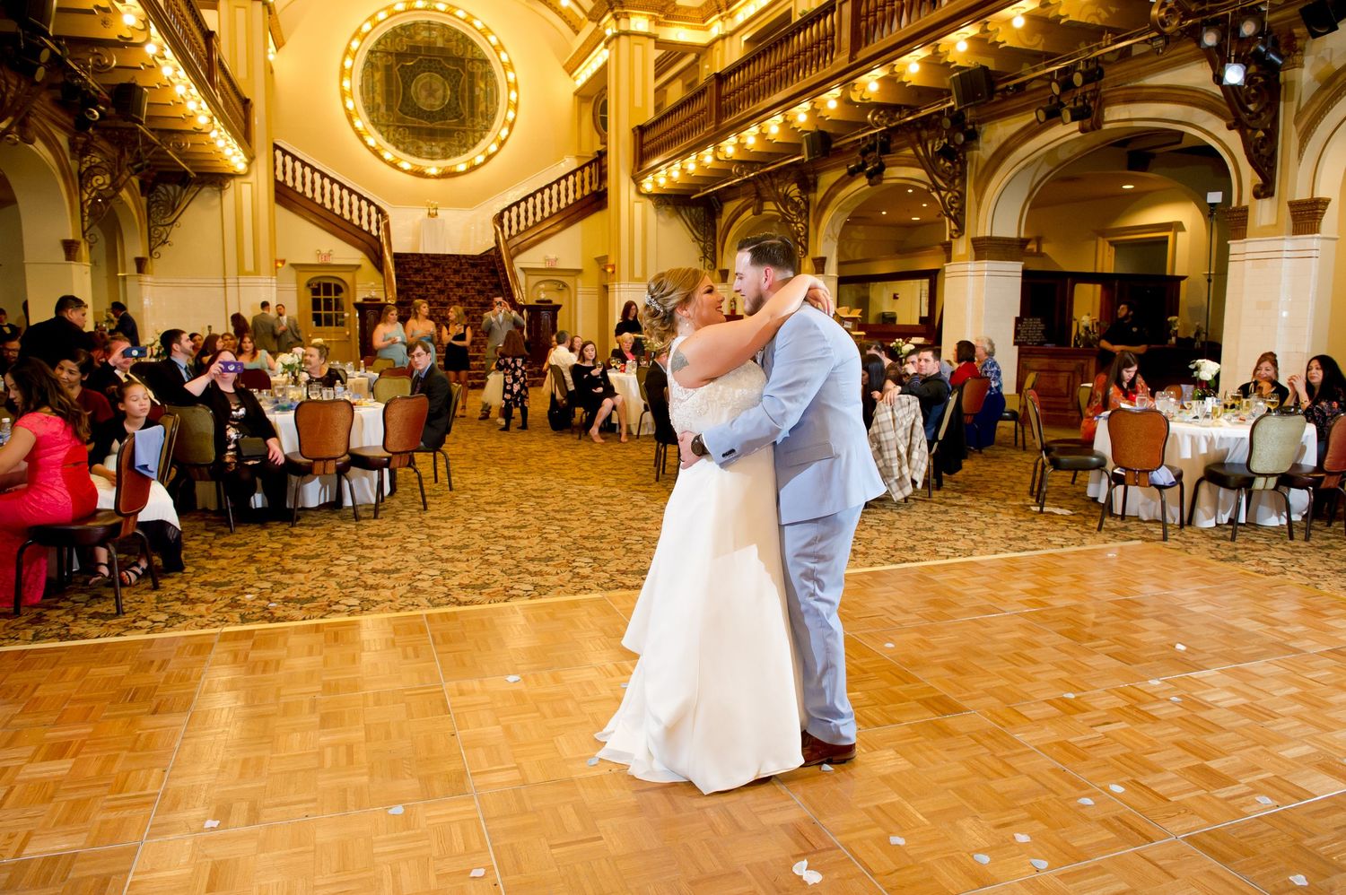 Elegant ballroom wedding reception with couples dancing on a polished wooden floor.