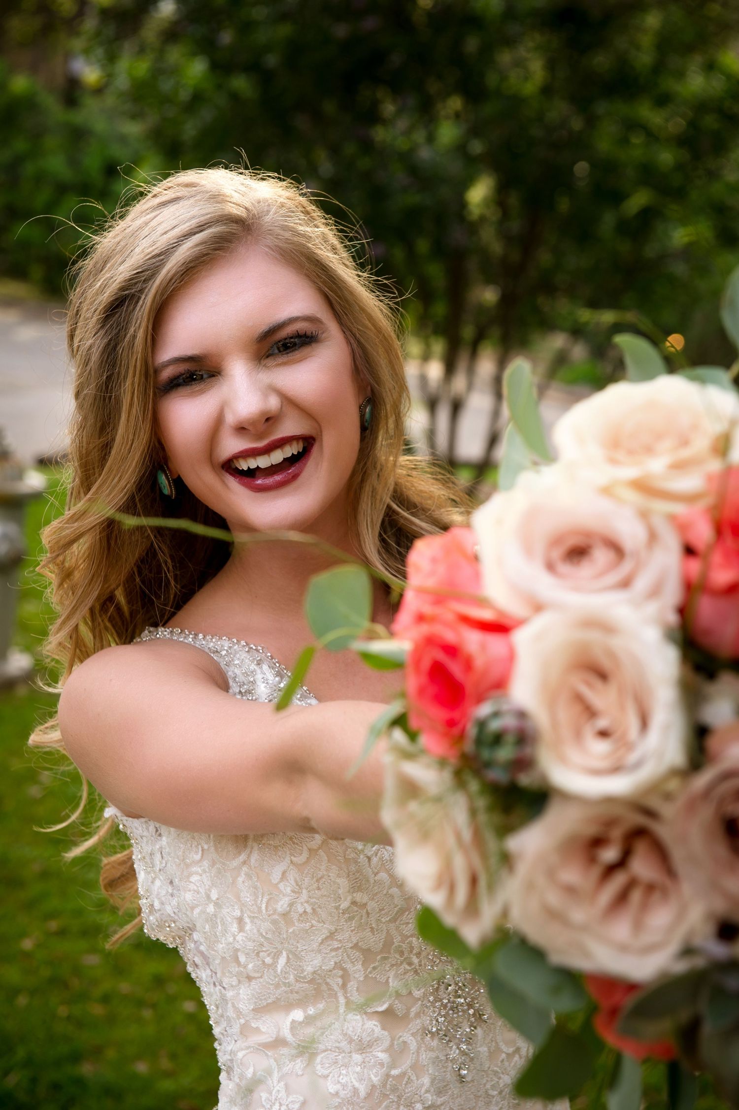 Close-up shots of bride holding coral and blush rose bouquet while twirling in her gown.