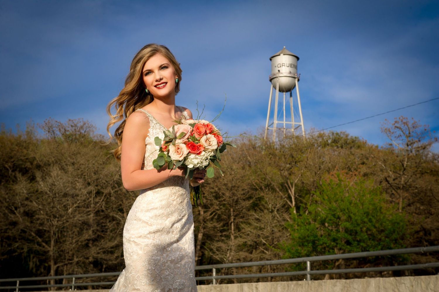 Bridal portrait with water tower and trees visible in the background against blue sky.
