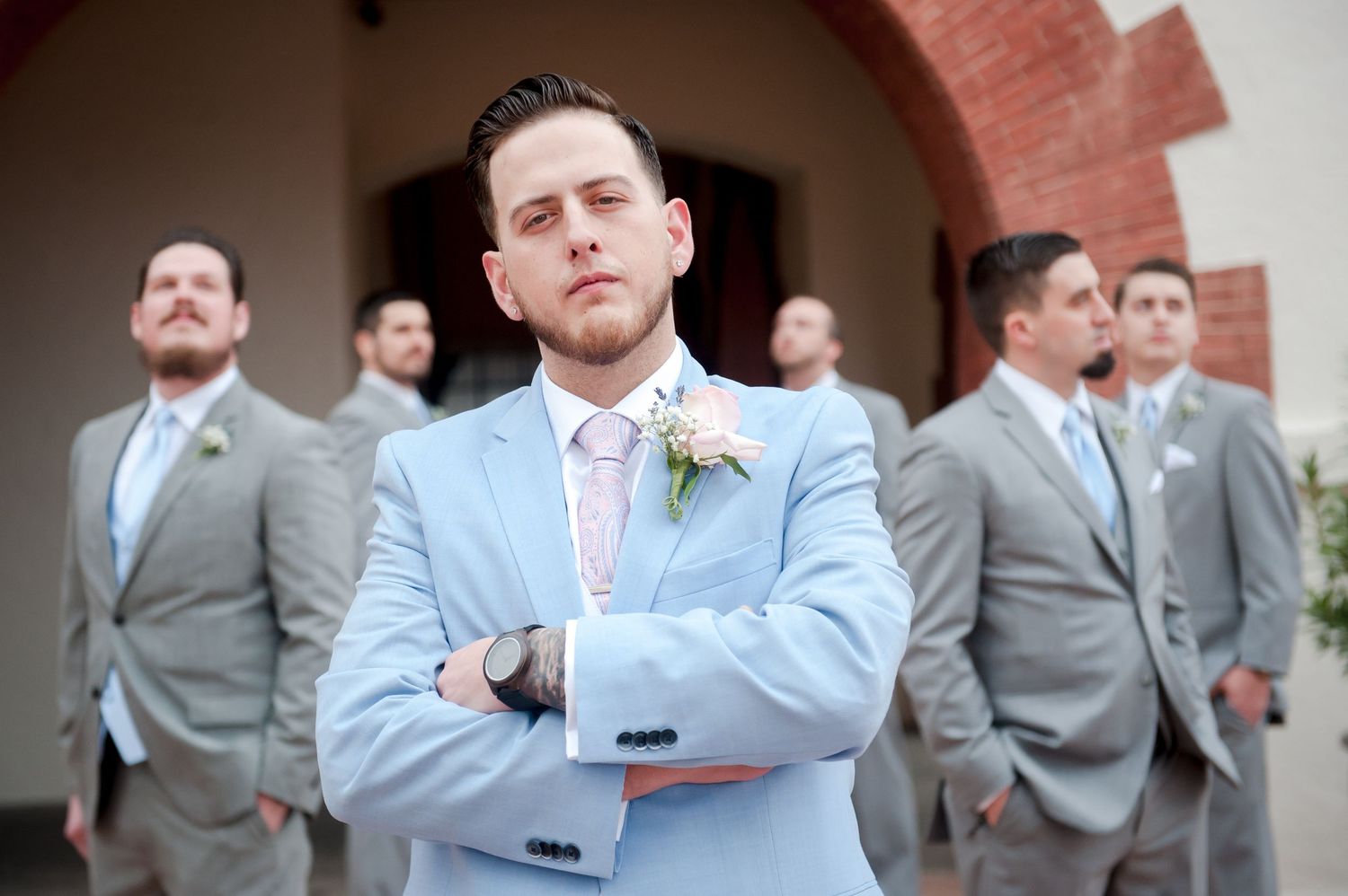 Groomsmen in light blue and gray suits pose for formal wedding photos.
