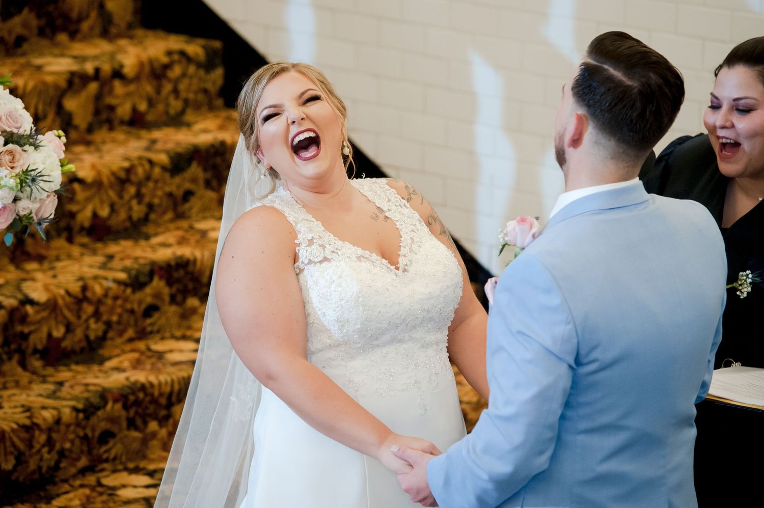 A joyful wedding ceremony moment captured on an ornate staircase with patterned carpet.