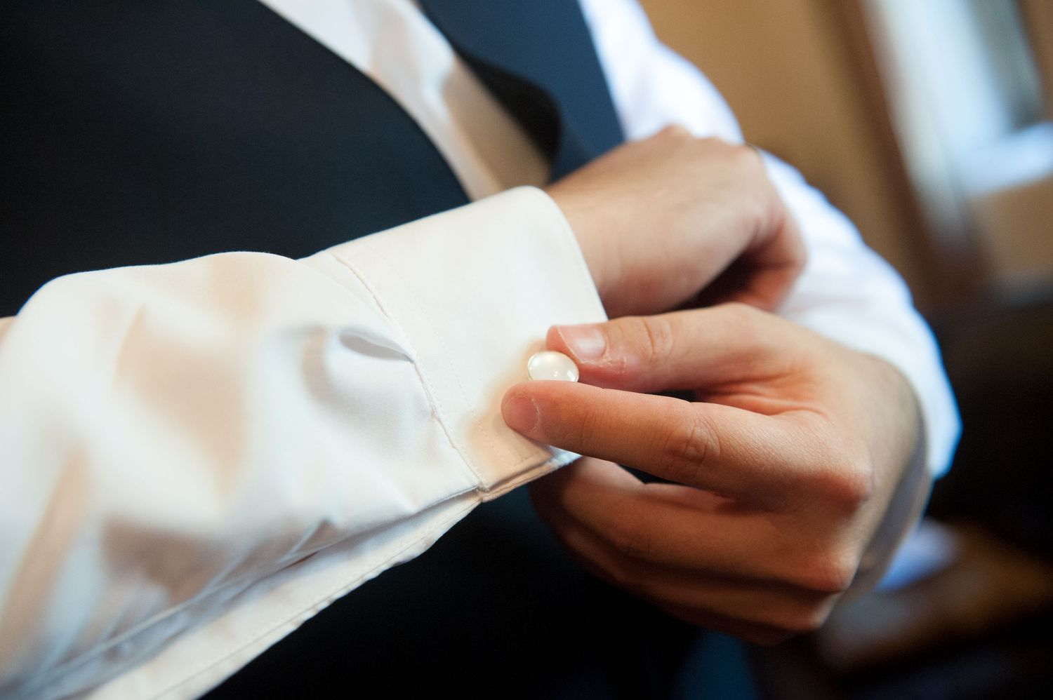 Close-up details of wedding day preparation showing hands adjusting cuffs.