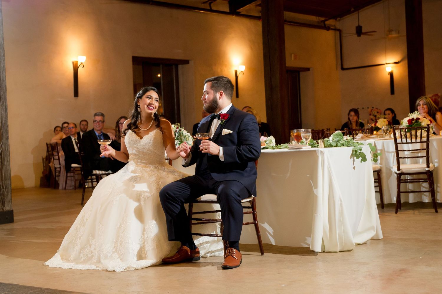 Wedding couple performs romantic dance in rustic reception hall with ambient lighting.