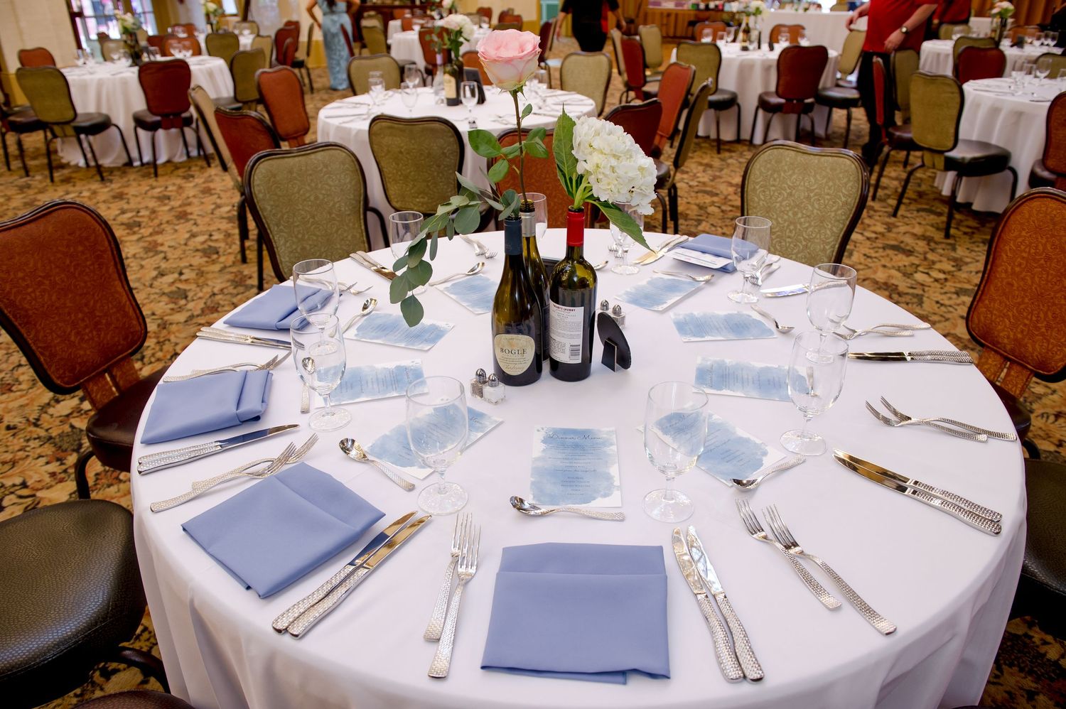 Formal dining room with round tables set with white linens and place settings.