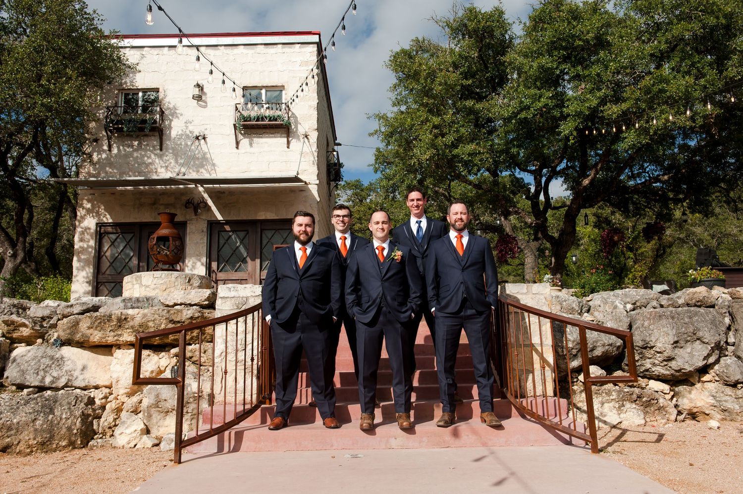 A panoramic sequence of wedding party photos taken on stone steps against a rustic Mediterranean backdrop.