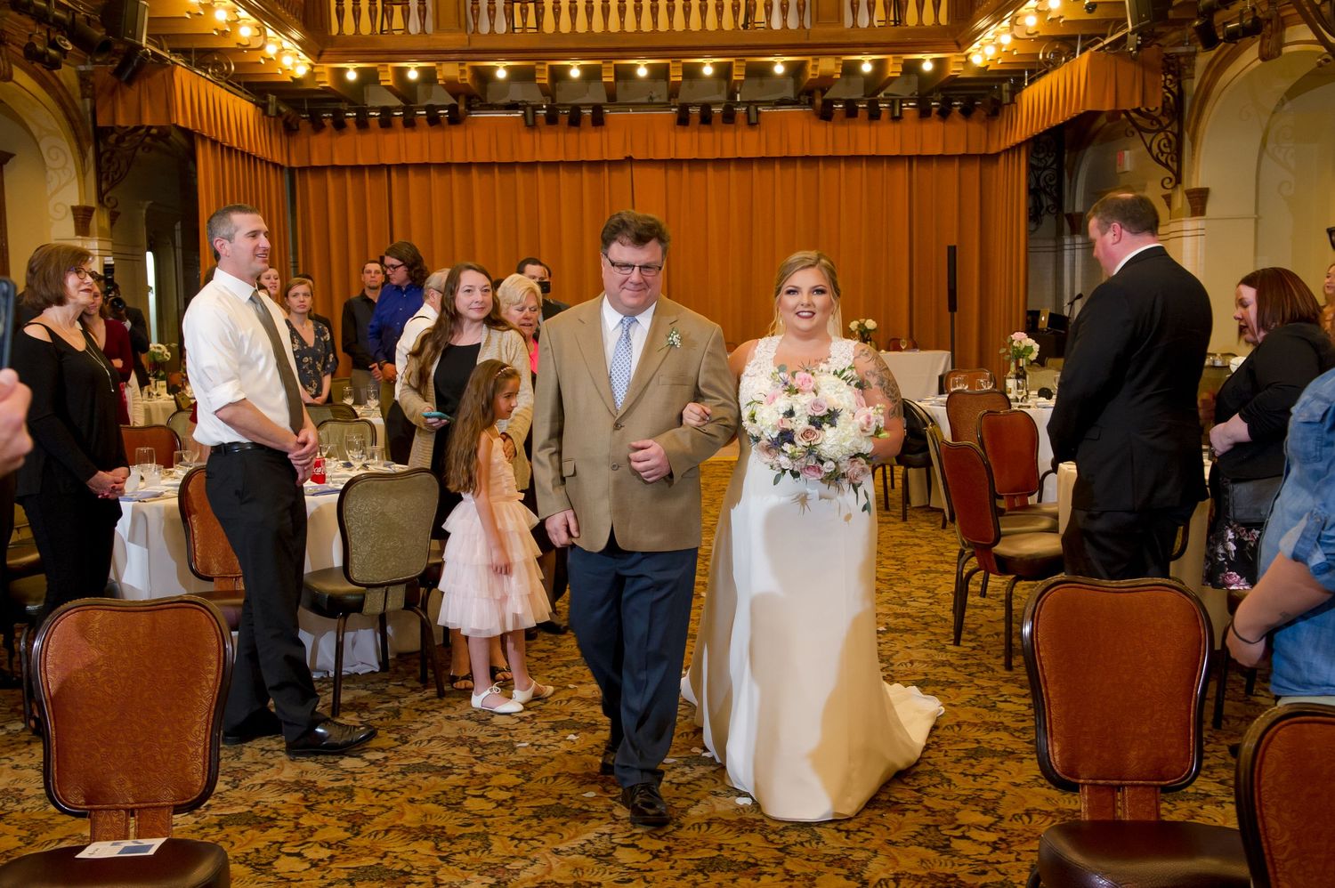 An ornate ballroom with wooden details and decorative ceiling features during a wedding celebration.