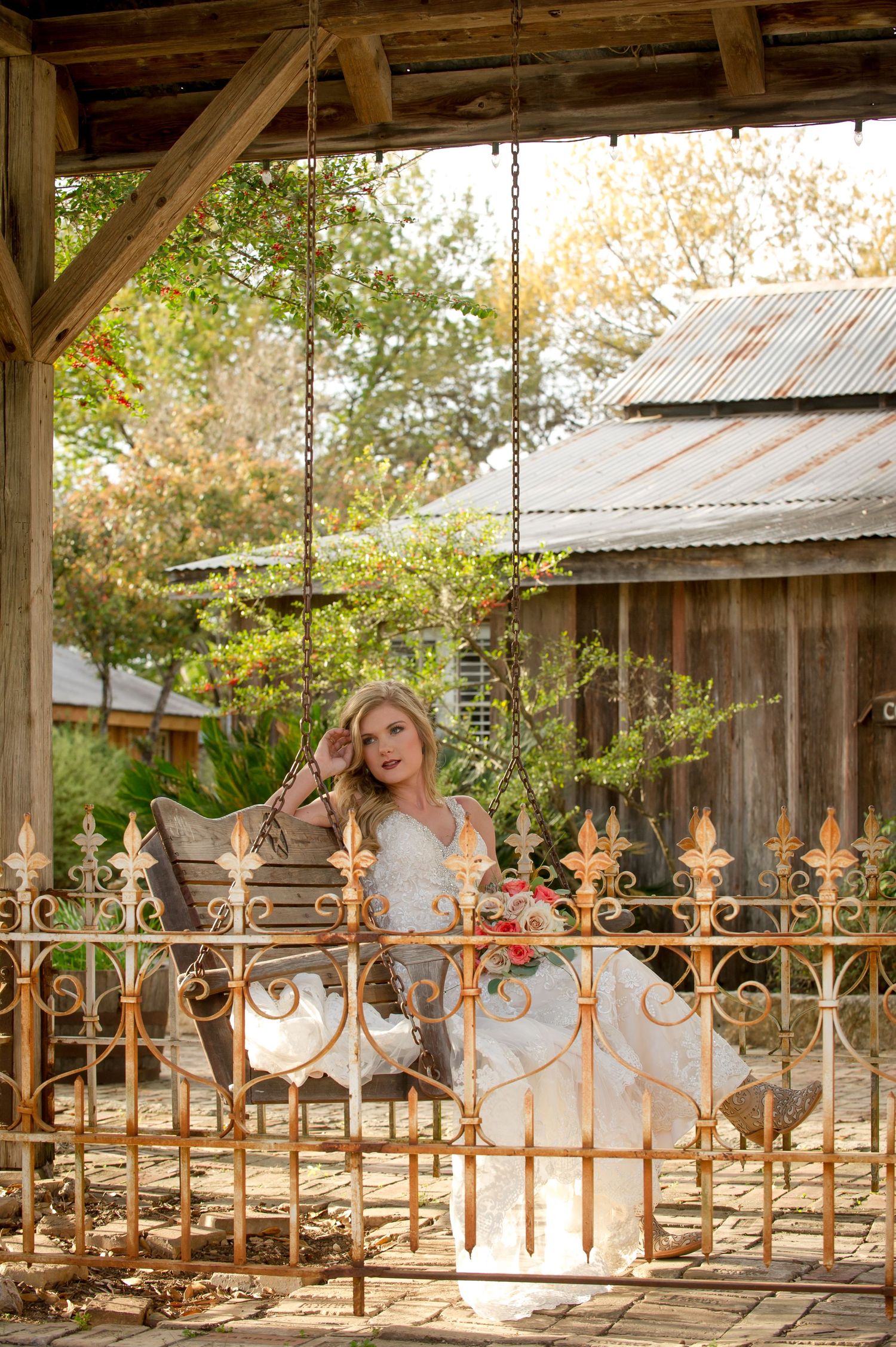 Rustic outdoor wedding venue with ornate metal railings and wooden pavilion structure.