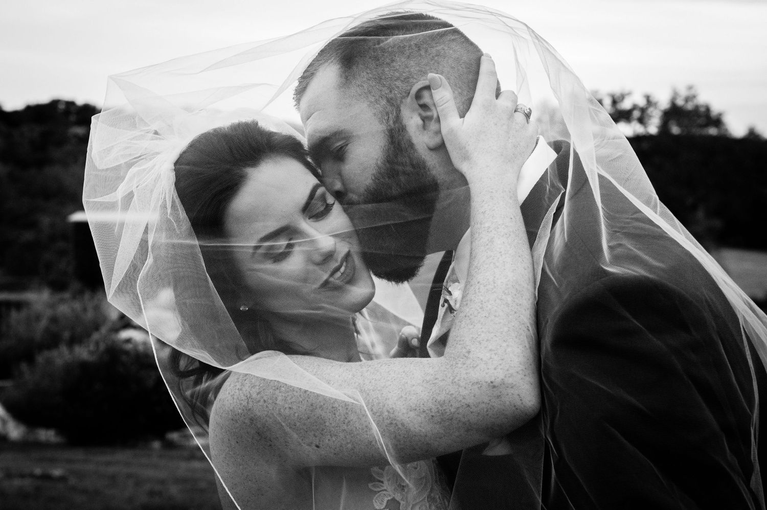 Romantic black and white wedding portraits with flowing veil creating artistic composition.