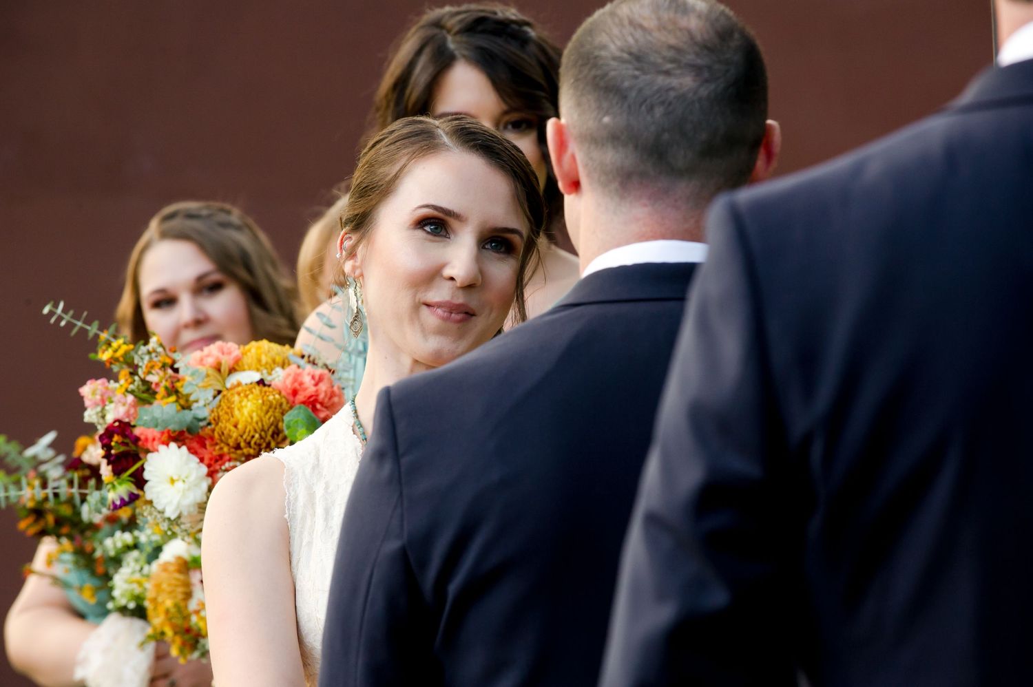 Outdoor wedding ceremony with guests gathered in rows of white chairs among garden landscaping.