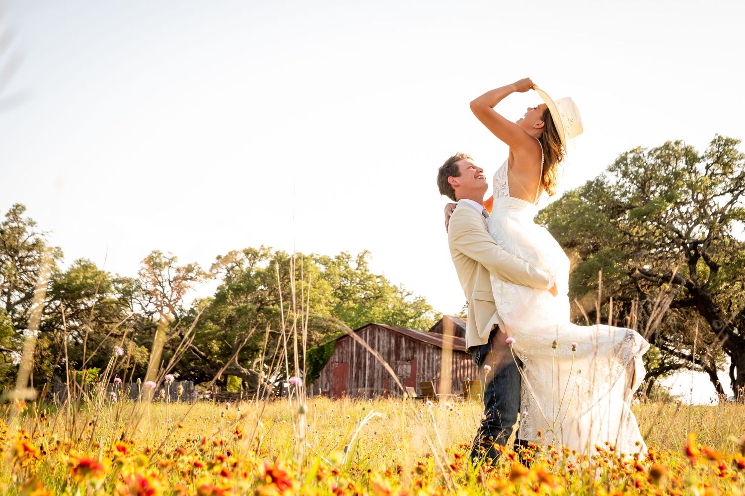 Romantic wedding portraits taken in a golden sunflower field at sunset.