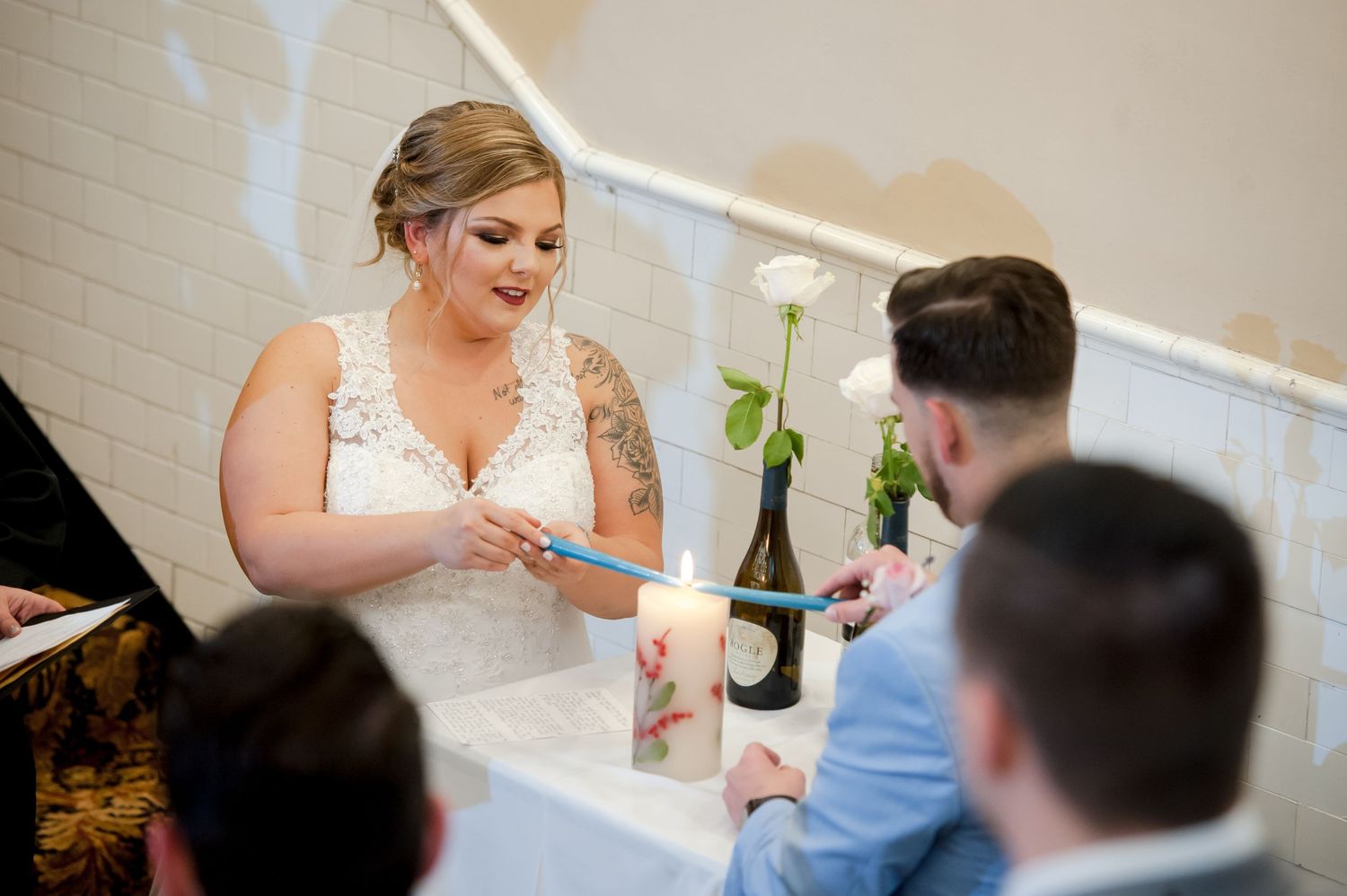 Wedding ceremony taking place in an elegant indoor venue with white brick walls and classic decor.