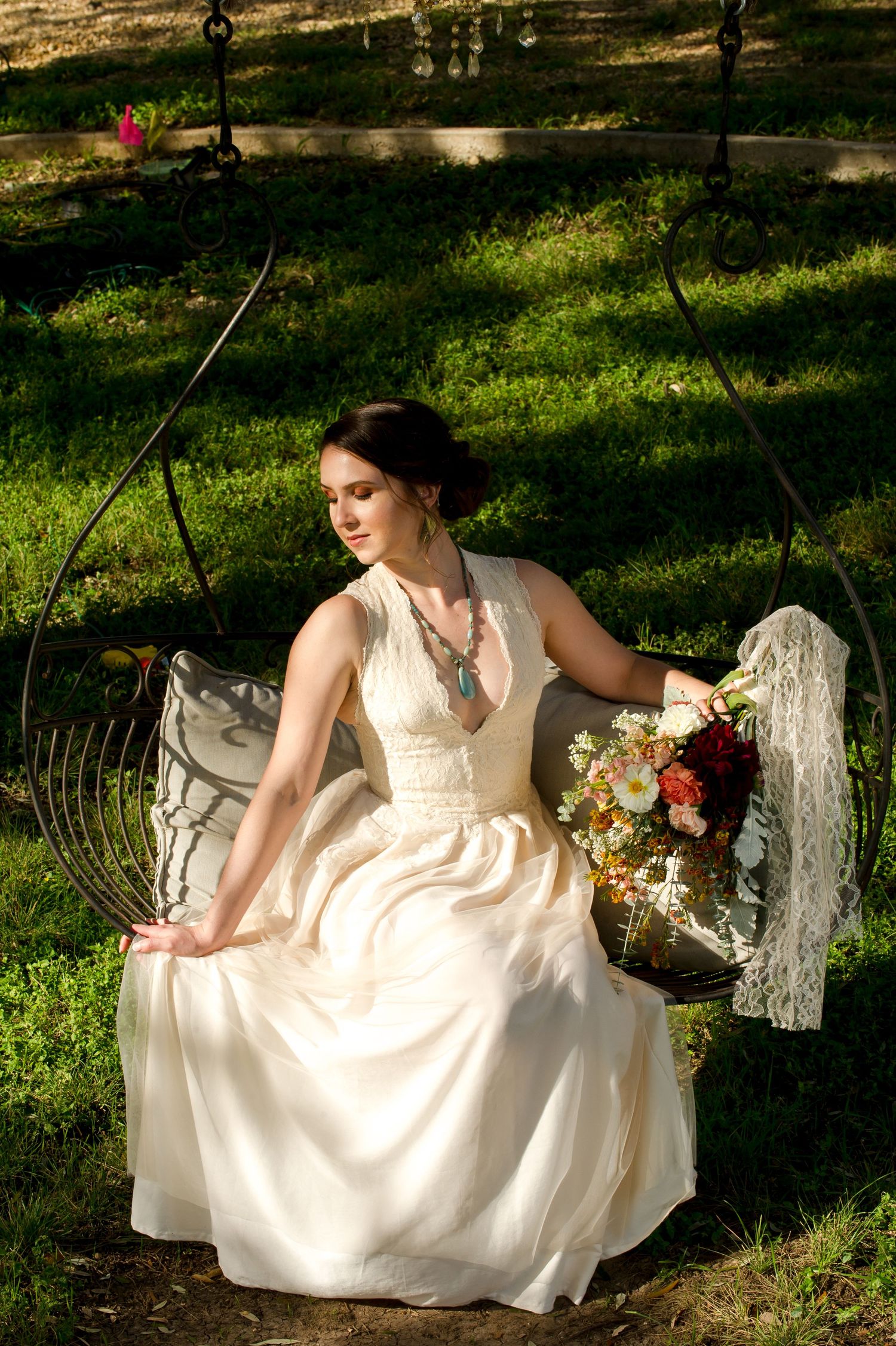 A person in a flowing white dress sits gracefully in a garden setting holding a bouquet of colorful flowers.