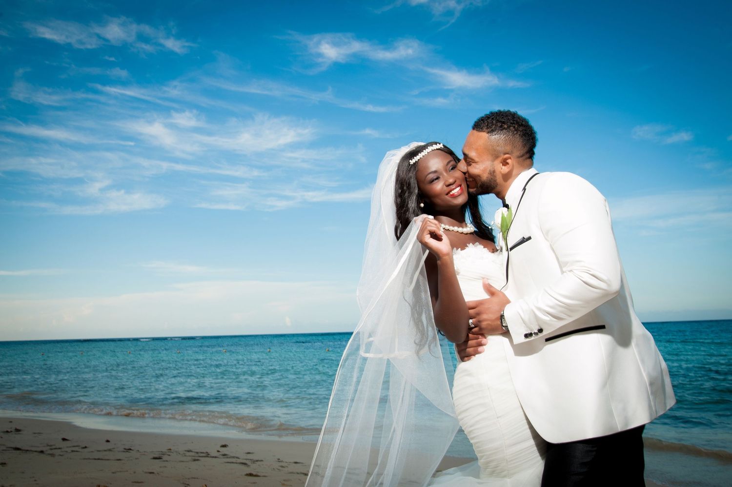 Romantic beach wedding photography sequence showing couple embracing against vibrant blue ocean and sky backdrop.
