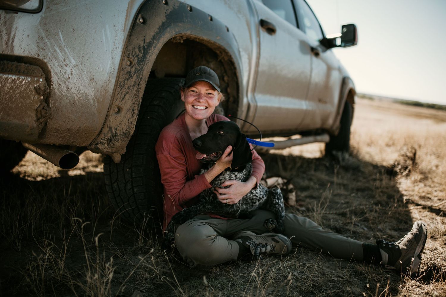 Image of Tori Anderson sitting against a truck tire with a dog