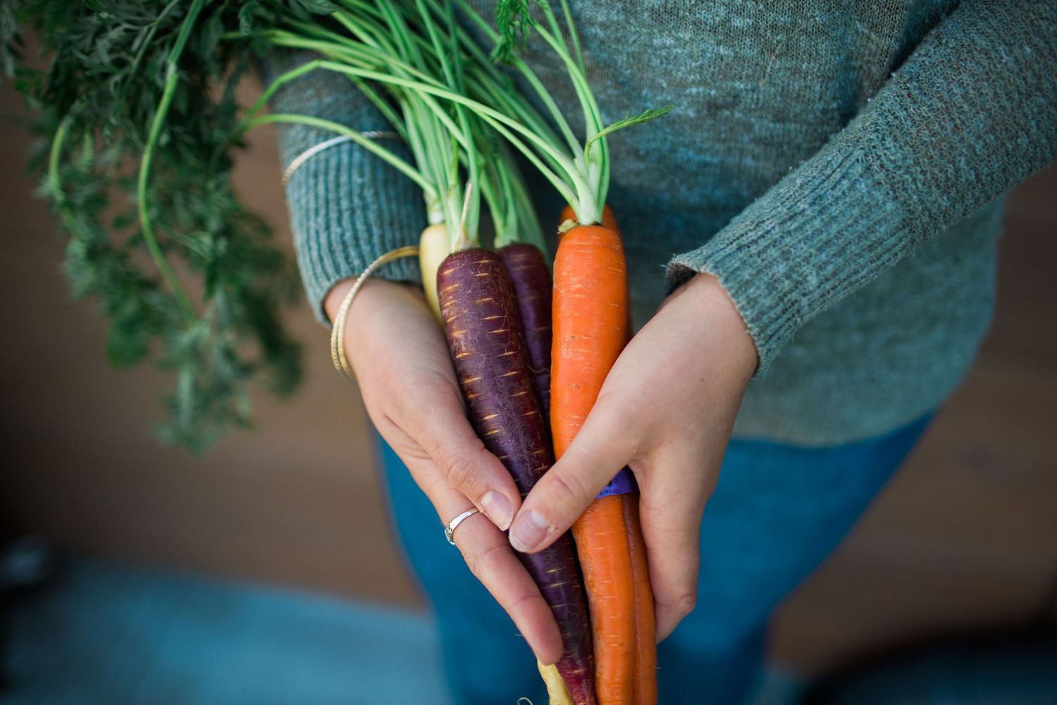 image of womans hands holding fresh colorful carrots