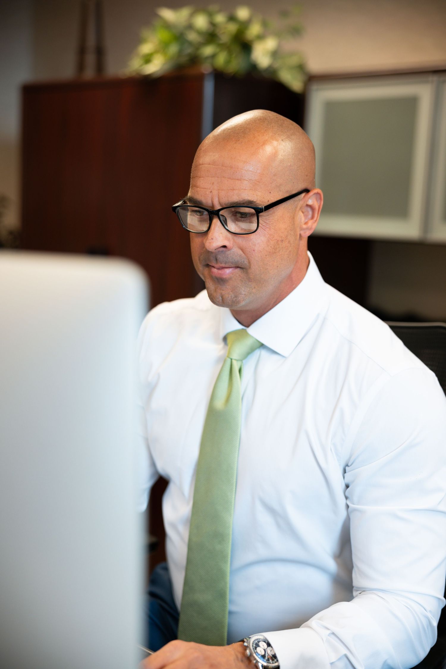 image of man wearing a tie and glasses working at computer