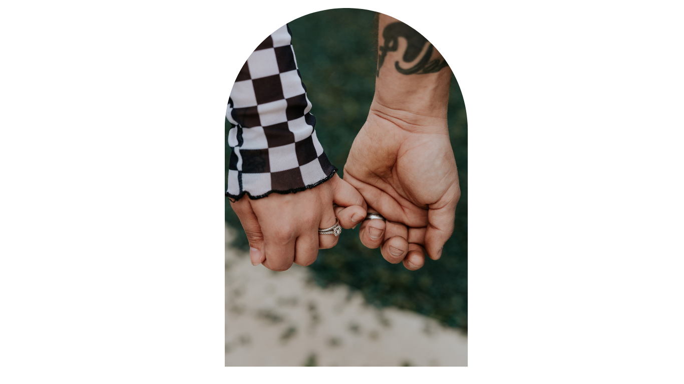 Close-up of couple holding hands, showing engagement ring and checkered sleeve tattoo detail.