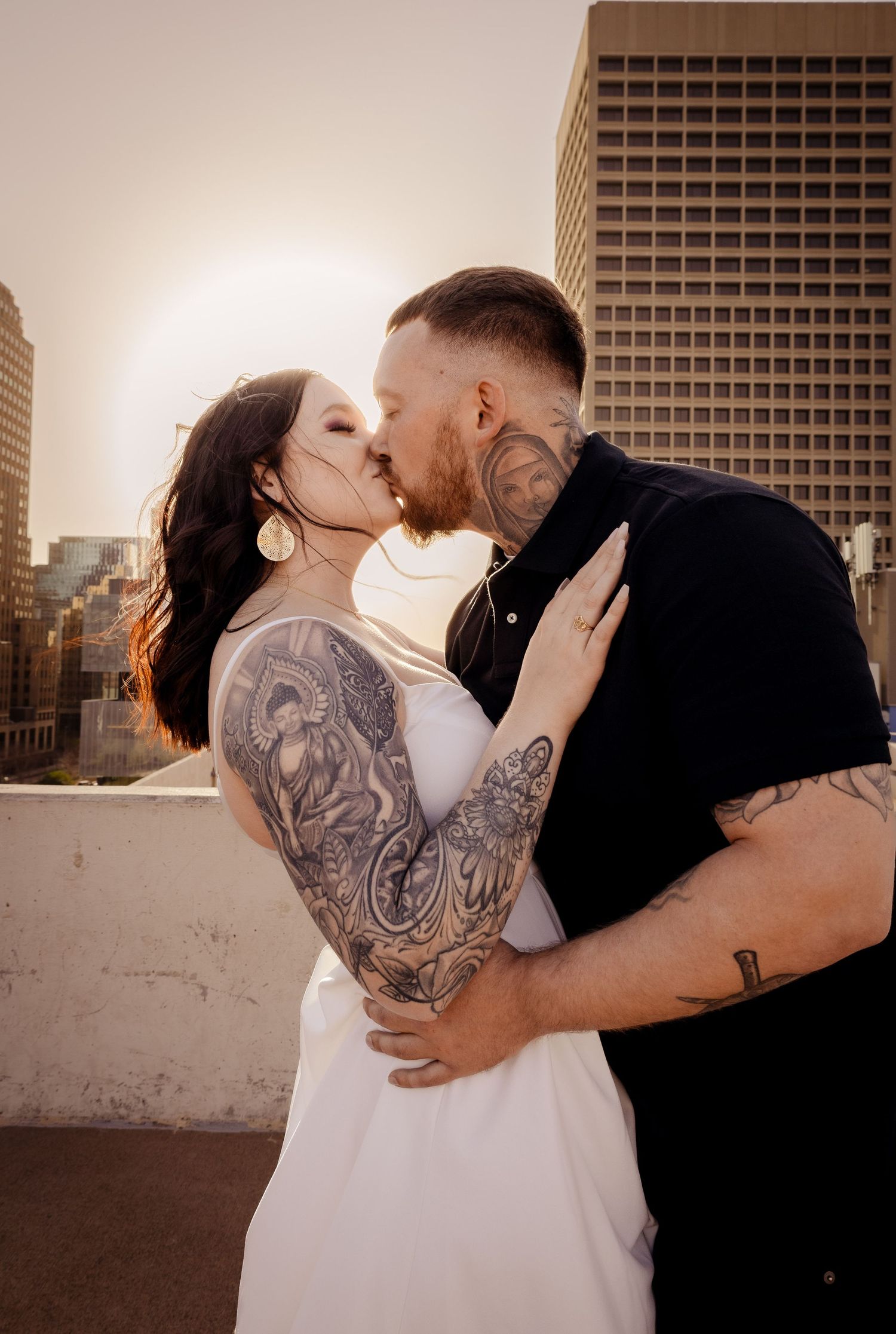 Couple sharing passionate kiss on rooftop at golden hour.