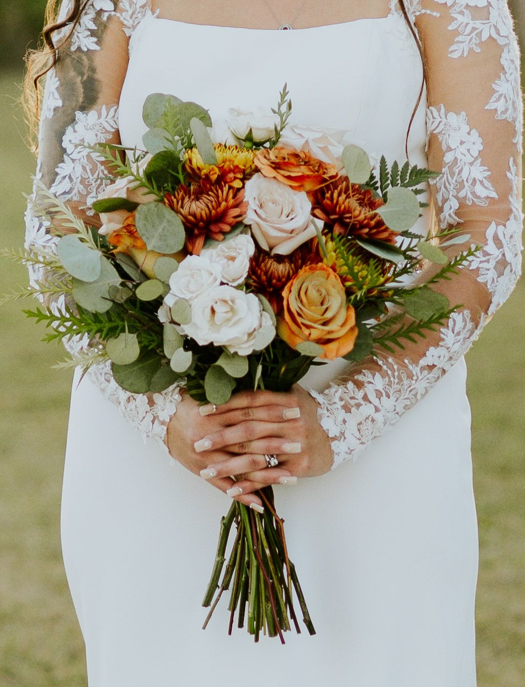 Close-up of bridal bouquet with orange chrysanthemums, roses, and eucalyptus.