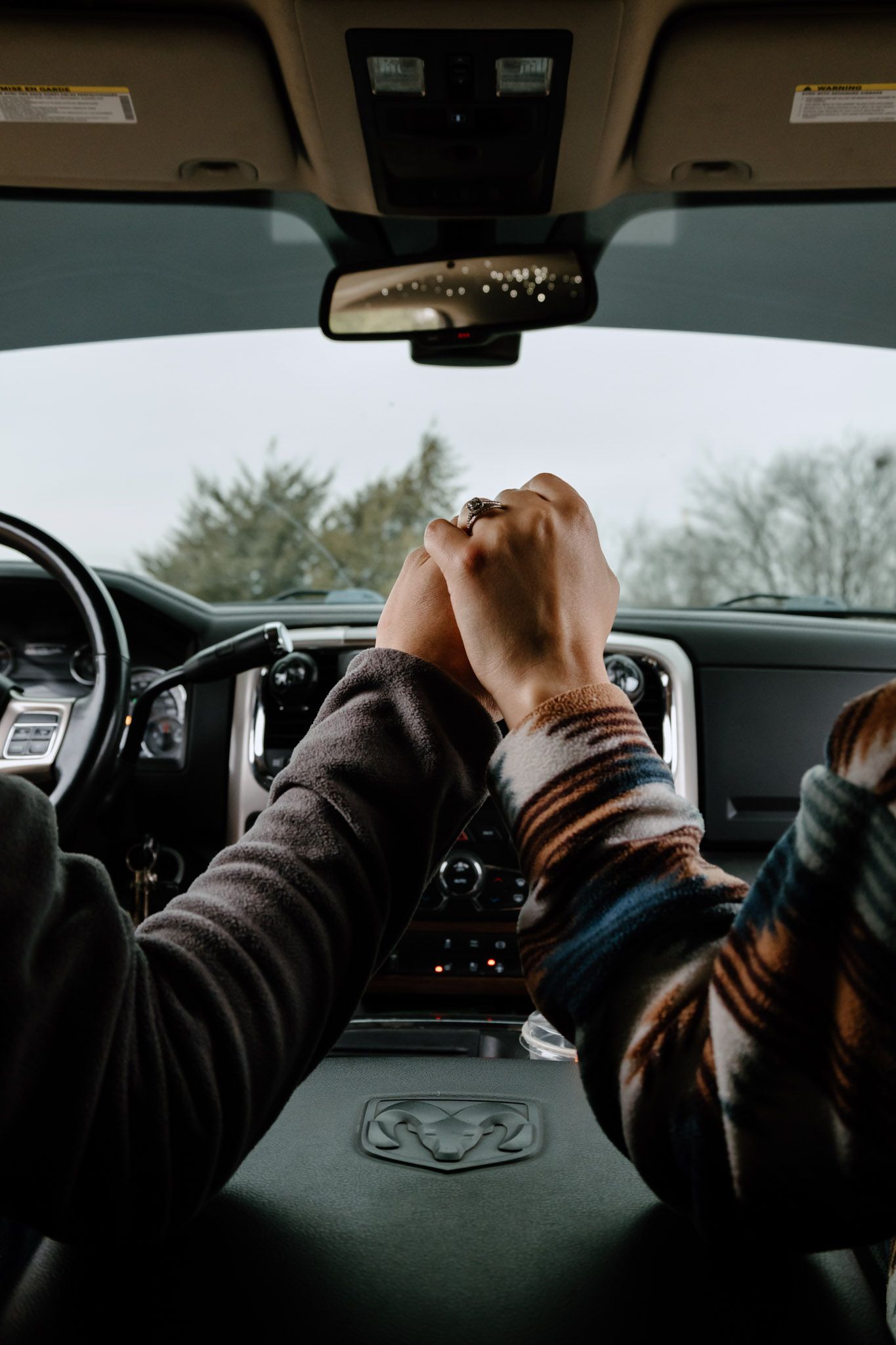 Couple holding hands inside a RAM truck cab viewed from the backseat perspective.