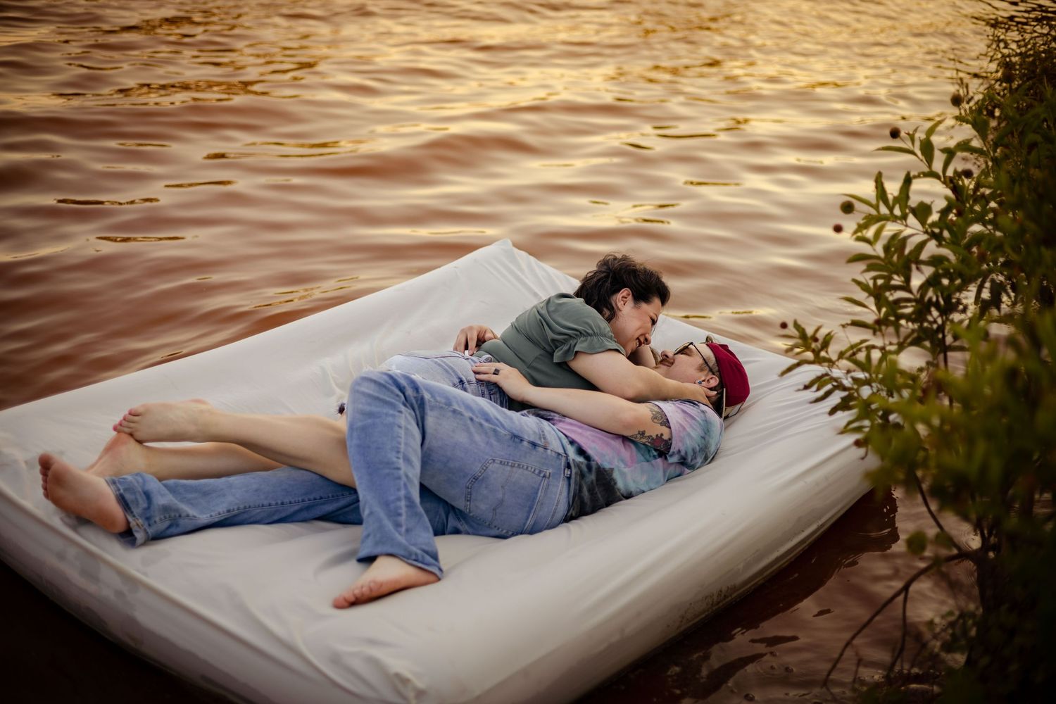 Romantic couple cuddling together on a floating mattress on a calm lake at sunset.