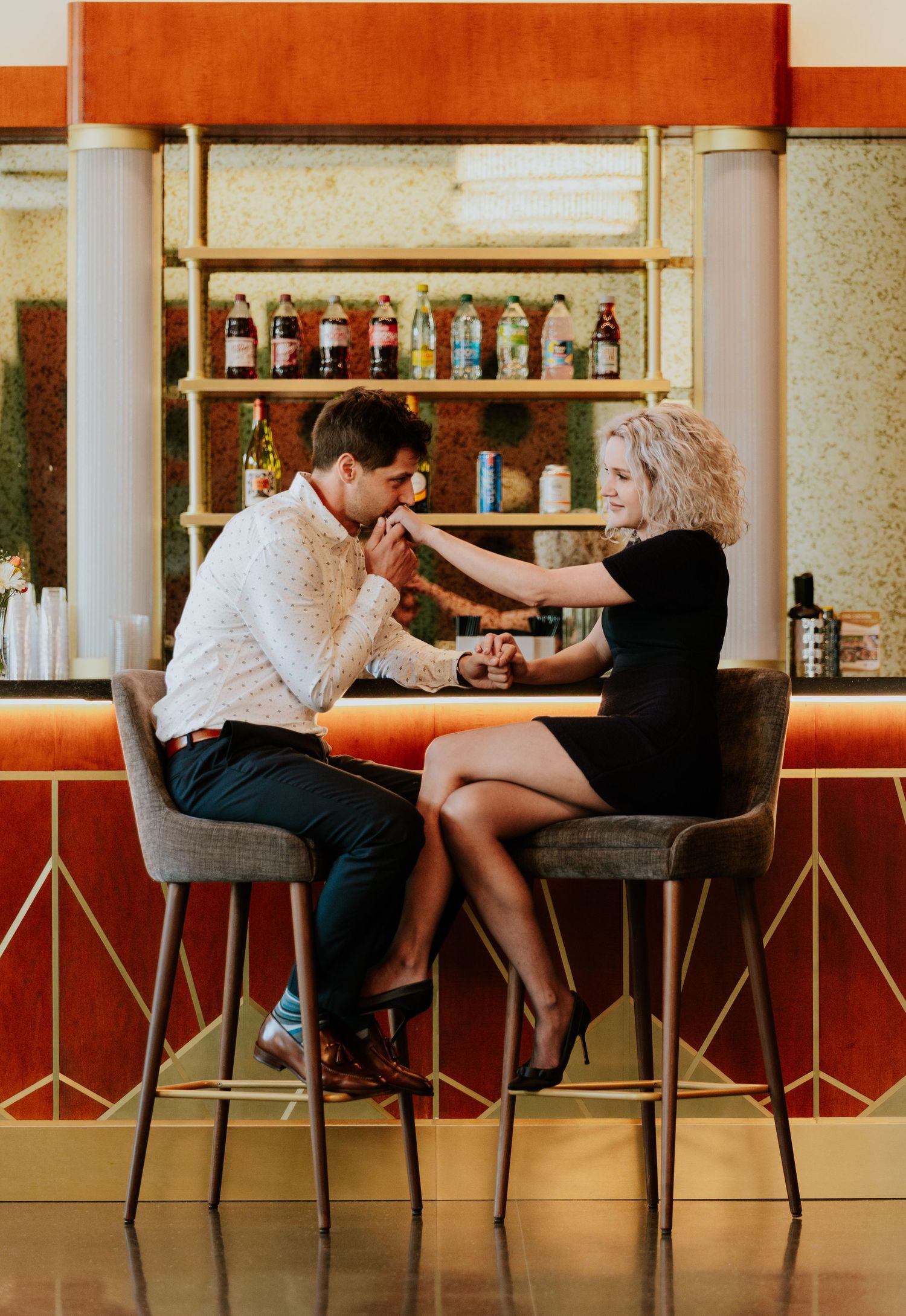 Couple sitting at a stylish retro bar, holding hands and sharing a romantic conversation.