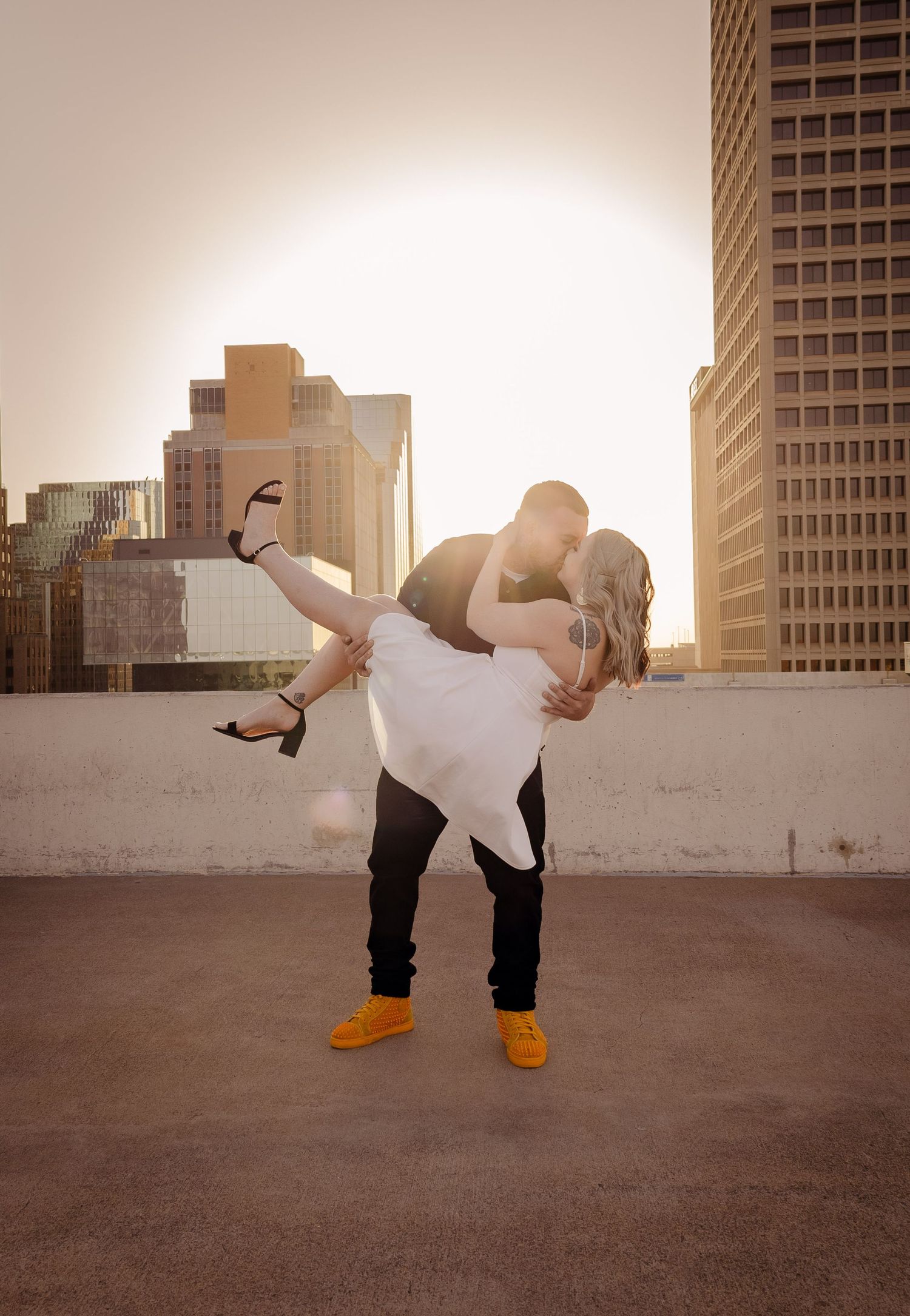 Romantic dip kiss on rooftop at sunset.