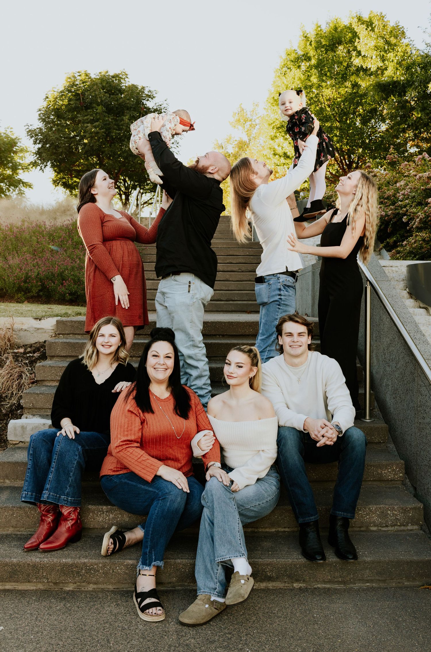 Large extended family poses together on outdoor staircase during fall family portrait session.